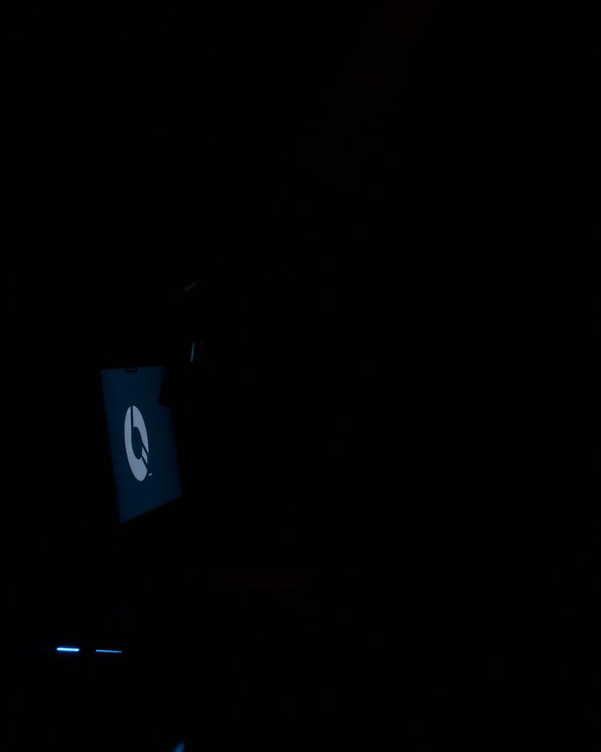 Dark studio desk with a microphone lit by a faint blue monitor glow