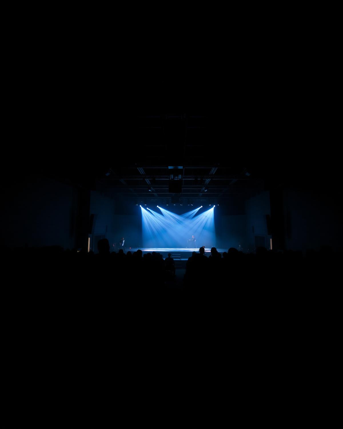 Darkened esports venue with blue stage lighting over silhouetted seating